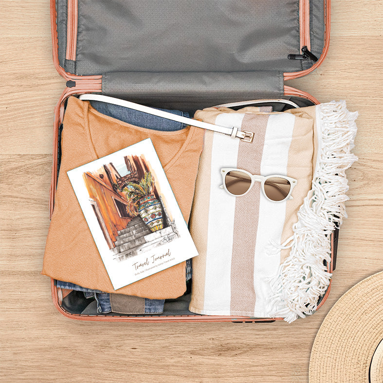 Reisetagebuch Italien mit handgezeichneter Illustration einer sizilianischen Straße mit bemalter Vase, bereit für die Reise im Koffer